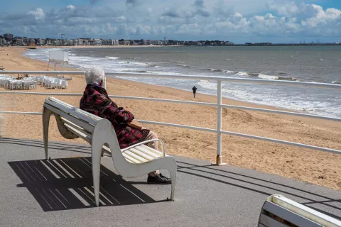 Vielle dame sur un banc qui regarde la mer