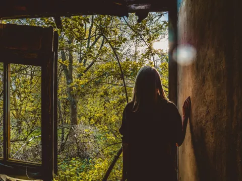 une femme qui souffre de douleur chronique regarde par la fenêtre