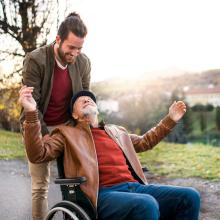 Un jeune homme pousse un vieil homme en fauteuil roulant