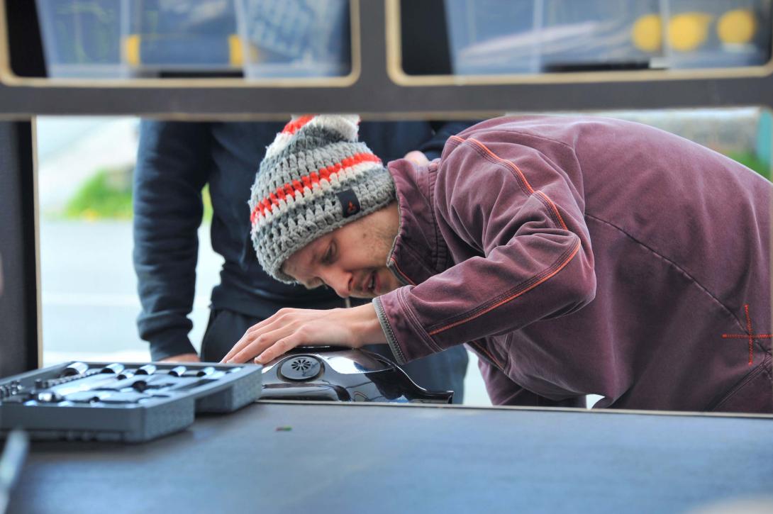 Un homme répare un appareil dans un Repair Café Mobile