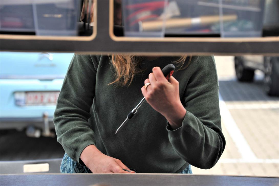 Une femme tient un tournevis devant un Repair Café Mobile