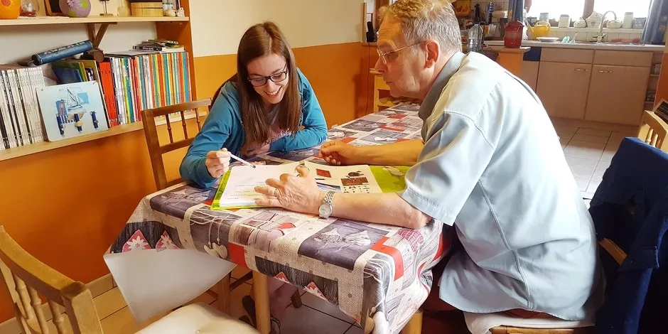 Un homme plus agé donne cours à une jeune fille dans le salon d'une maison. 